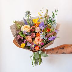 a person holding a bouquet of flowers in their hand with tattoos on the arm and arms