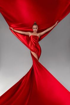 a woman in a red dress is posing with her hands on the fabric