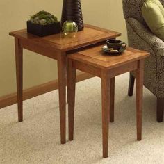 two wooden tables sitting on top of a carpeted floor next to a green chair