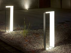 three lights are lit up on the ground in front of a building at night time