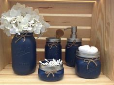 three mason jars with white flowers in them and soap dispenser on the shelf