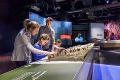 two adults and three children looking at a model of a city on display in a museum