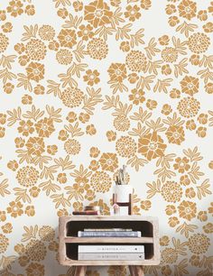 a table with books and a vase on it next to a wallpapered background