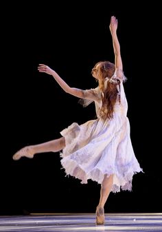 a woman in a white dress is doing a dance move with her legs spread out