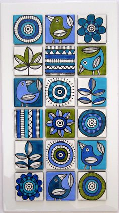 a blue and green tile with flowers on the bottom is in a white frame,