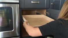 a woman opening a cabinet in the kitchen