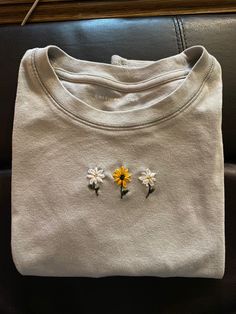 three flowers are placed on the front of a white shirt with yellow and white daisies