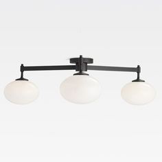 three light ceiling fixture with white glass globes on an adjustable track and black metal frame