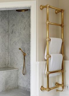 a gold towel rack in a bathroom next to a shower