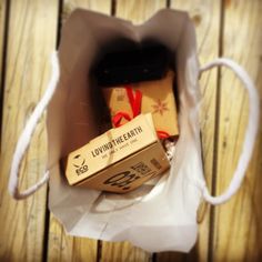 two wrapped presents in a brown paper bag on a wooden table with string and twine