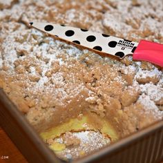 a pink and black polka dot knife sitting on top of a pan filled with powdered sugar