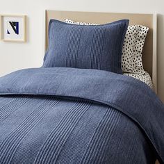 a bed with blue bedspread and two pillows on top of the headboard