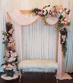 an image of a wedding ceremony setup with flowers and greenery on the wall behind it