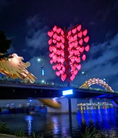 the lights are lit up in the shape of hearts on top of a bridge over water