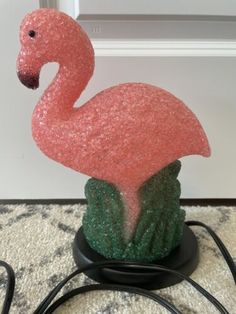 a pink flamingo statue sitting on top of a table next to a power cord