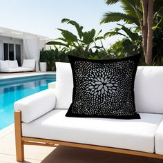 a black and white pillow sitting on top of a couch next to a swimming pool