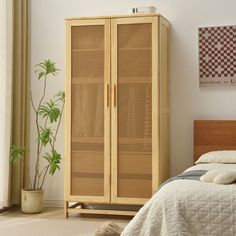 a bedroom with a bed and a wooden armoire next to a potted plant