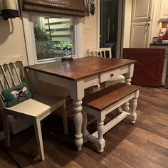 a kitchen table with two chairs and a bench in front of the window next to it