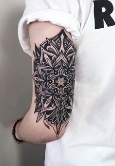 a man's arm with a black and white tattoo design on the left arm