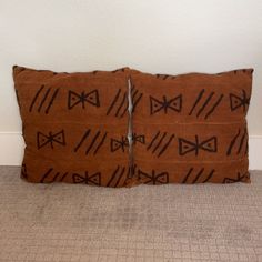 two brown decorative pillows sitting on top of a carpeted floor next to a wall