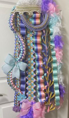 a bunch of ribbons hanging from the side of a door with bows and feathers on it