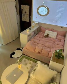 a bed with pink sheets and pillows in front of a projector screen on the wall