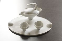 a white plate with four small bowls and a large bird figurine on it