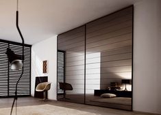 a modern bedroom with black and white striped wallpaper, large sliding closet doors, an eave lamp and a chair in the foreground