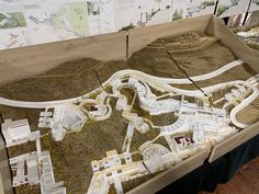 a model of a city with roads and buildings on display in a museum exhibit area