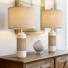 two lamps sitting on top of a wooden dresser