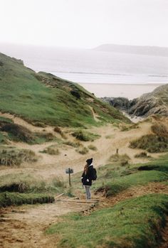 a person walking down a path near the ocean