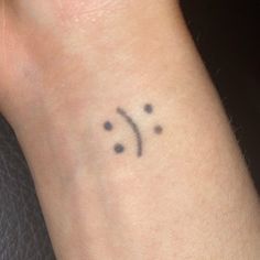 a small tattoo on the wrist of a woman's left arm, which has three dots in it