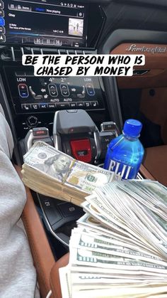 a car dashboard with cash and water in the center console, on top of a pile of bills