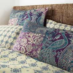 a bed topped with lots of pillows next to a wooden headboard