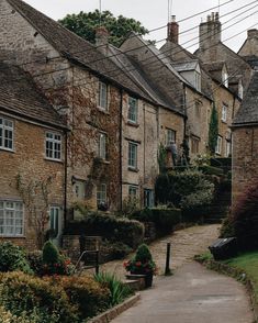 an alley way with stone buildings and flowers in the foreground on a cloudy day