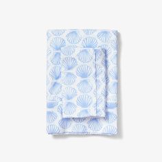 the blue and white shell print pocket square is folded on top of an unbuttoned sheet