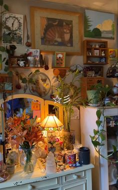 a white dresser topped with lots of vases and plants