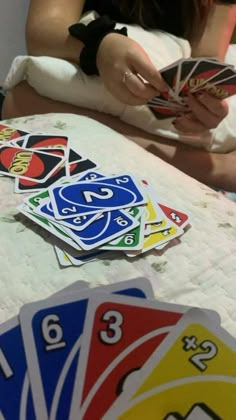 a woman sitting on top of a bed holding a card game in front of her face