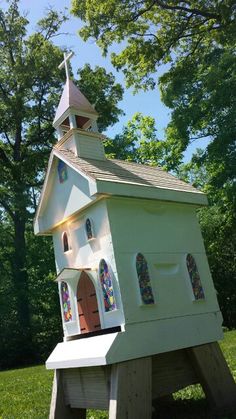 a small white church with stained glass windows and a steeple on the roof is shown in front of some trees