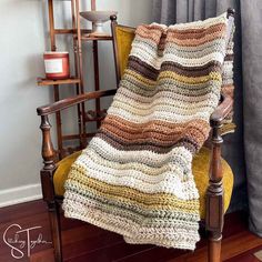 a crocheted blanket sitting on top of a wooden chair next to a window