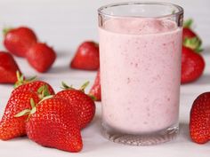 a glass filled with strawberry milk surrounded by strawberries