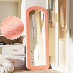 a pink mirror sitting on top of a wooden floor next to a white dresser and chair