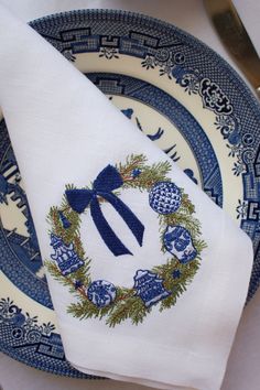 a blue and white plate topped with a christmas wreath napkin on top of a table