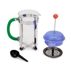 a glass french press coffee maker next to a grater and strainer on a white background