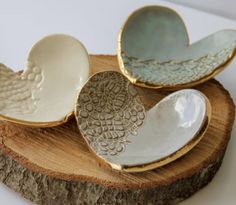 three ceramic dishes sitting on top of a piece of wood