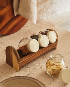 four eggs are in a wooden container on the counter next to two plates and spoons