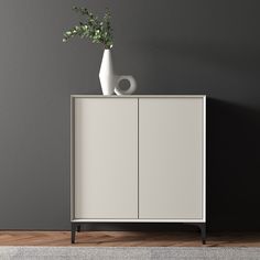 a vase with flowers sitting on top of a white cabinet next to a gray wall