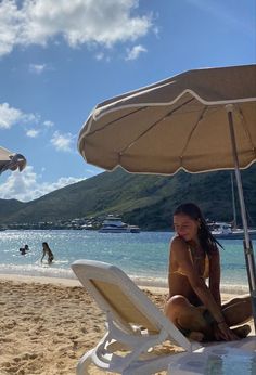 a woman sitting under an umbrella on the beach