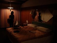 two people are standing in the dark near a bed