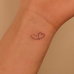 a small tattoo on the wrist of a woman with a heart in it's center